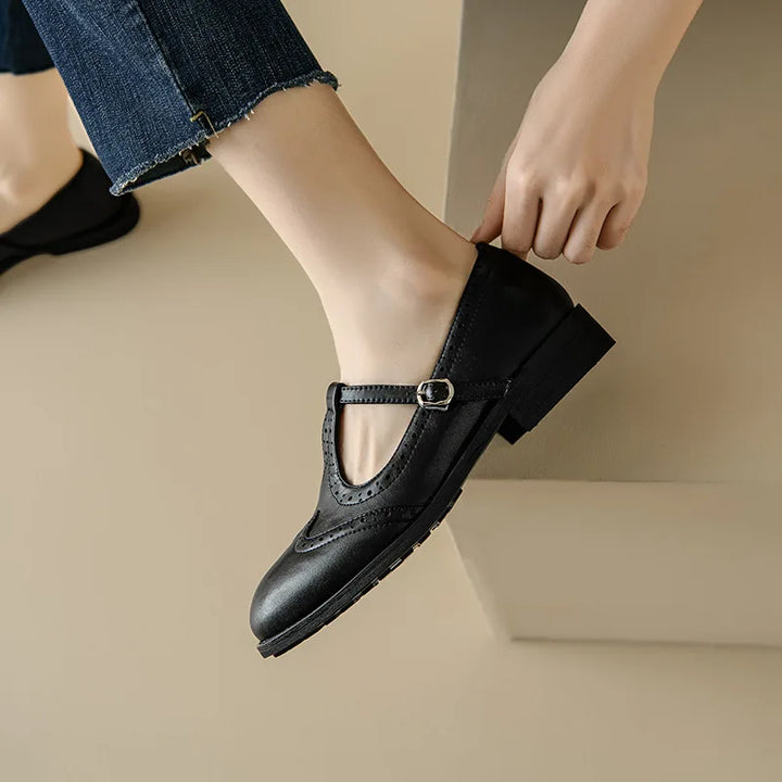 Brown and black Mary Jane shoes with brogue perforations and a T-bar buckle strap