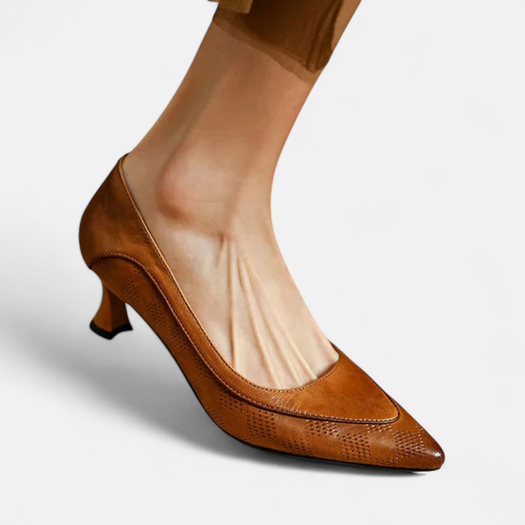 A woman wearing black pointed kitten-heel pumps with a subtle embossed finish.
