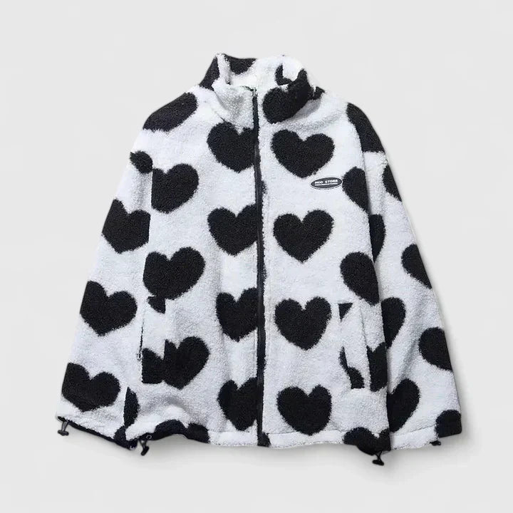 A woman wearing a plush white zip jacket with a bold black heart print and a high collar.