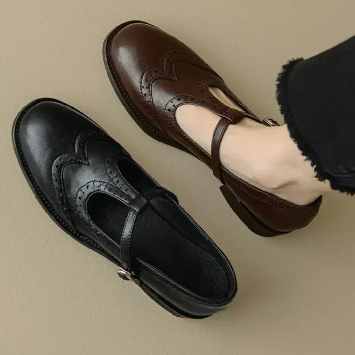 Brown and black Mary Jane shoes with brogue perforations and a T-bar buckle strap