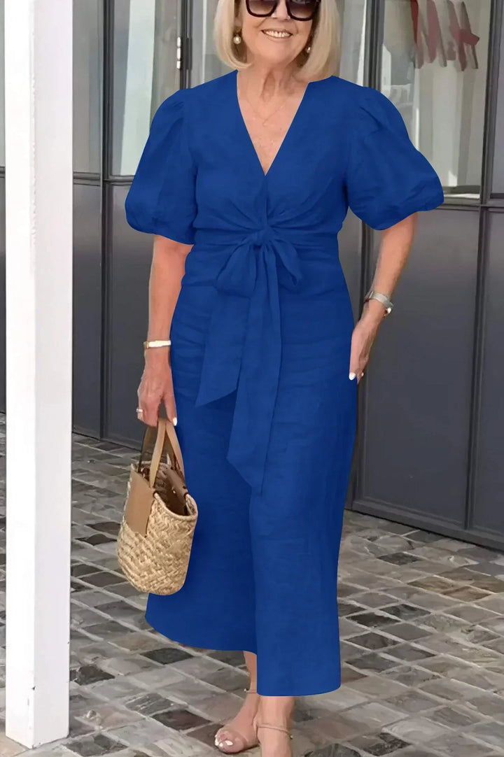 Woman wearing the Bridget bow-front midi dress with puff sleeves at a garden party.