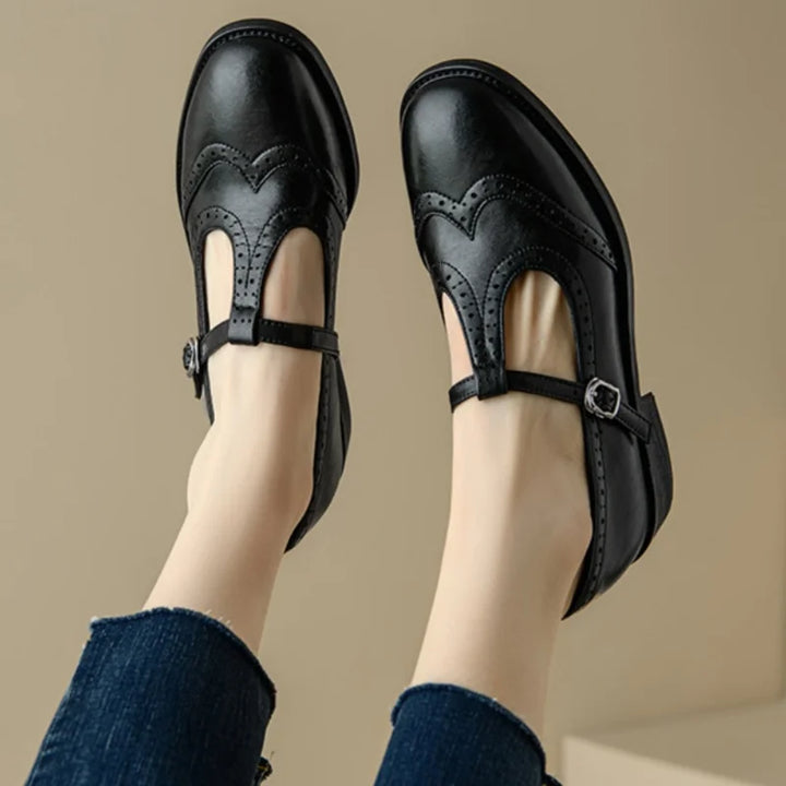 Brown and black Mary Jane shoes with brogue perforations and a T-bar buckle strap