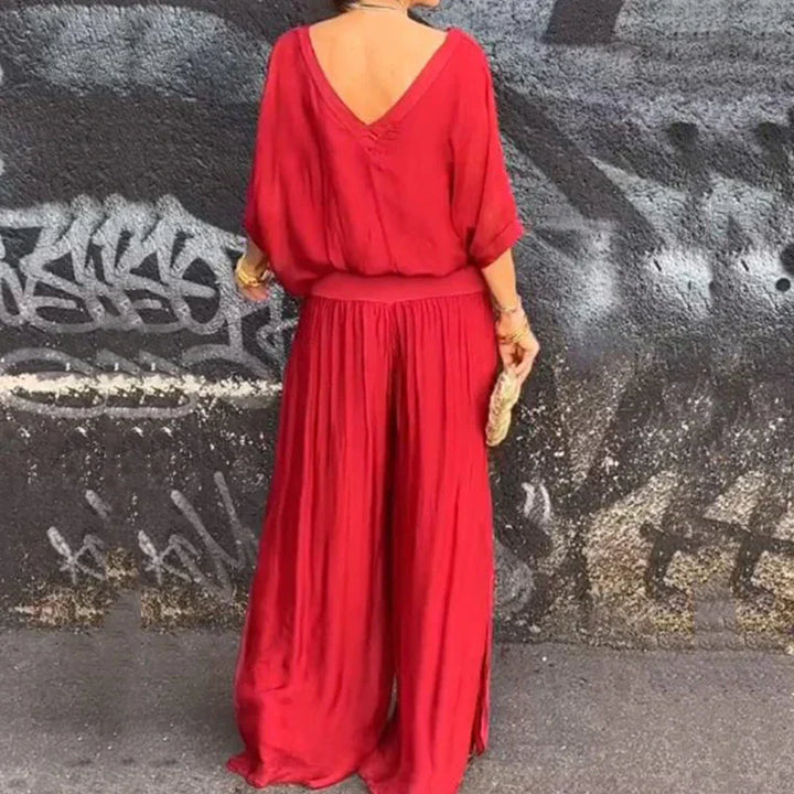 A woman wearing a flowing lounge two-piece set with a V-neck top and wide-leg trousers.