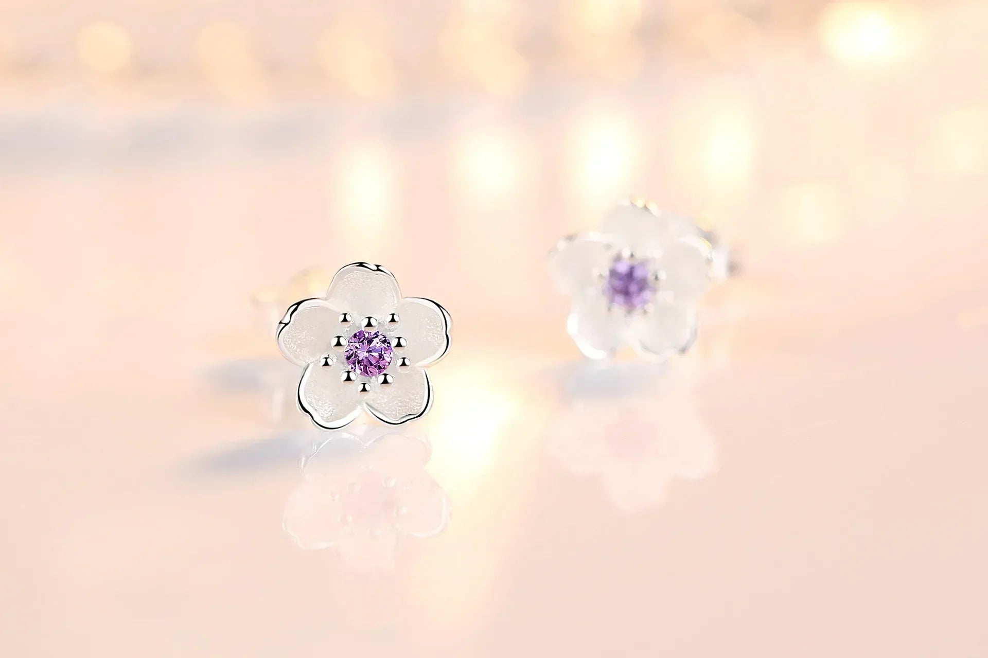 A pair of fine floral stud earrings in polished silver set with pink and purple zirconia stones