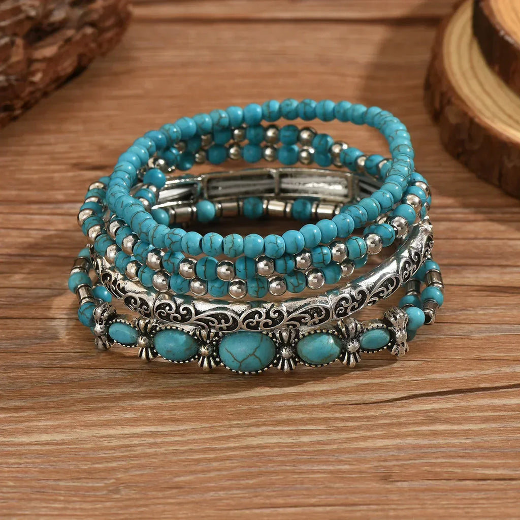 Set of turquoise and metallic boho-style stacking bracelets on a white background