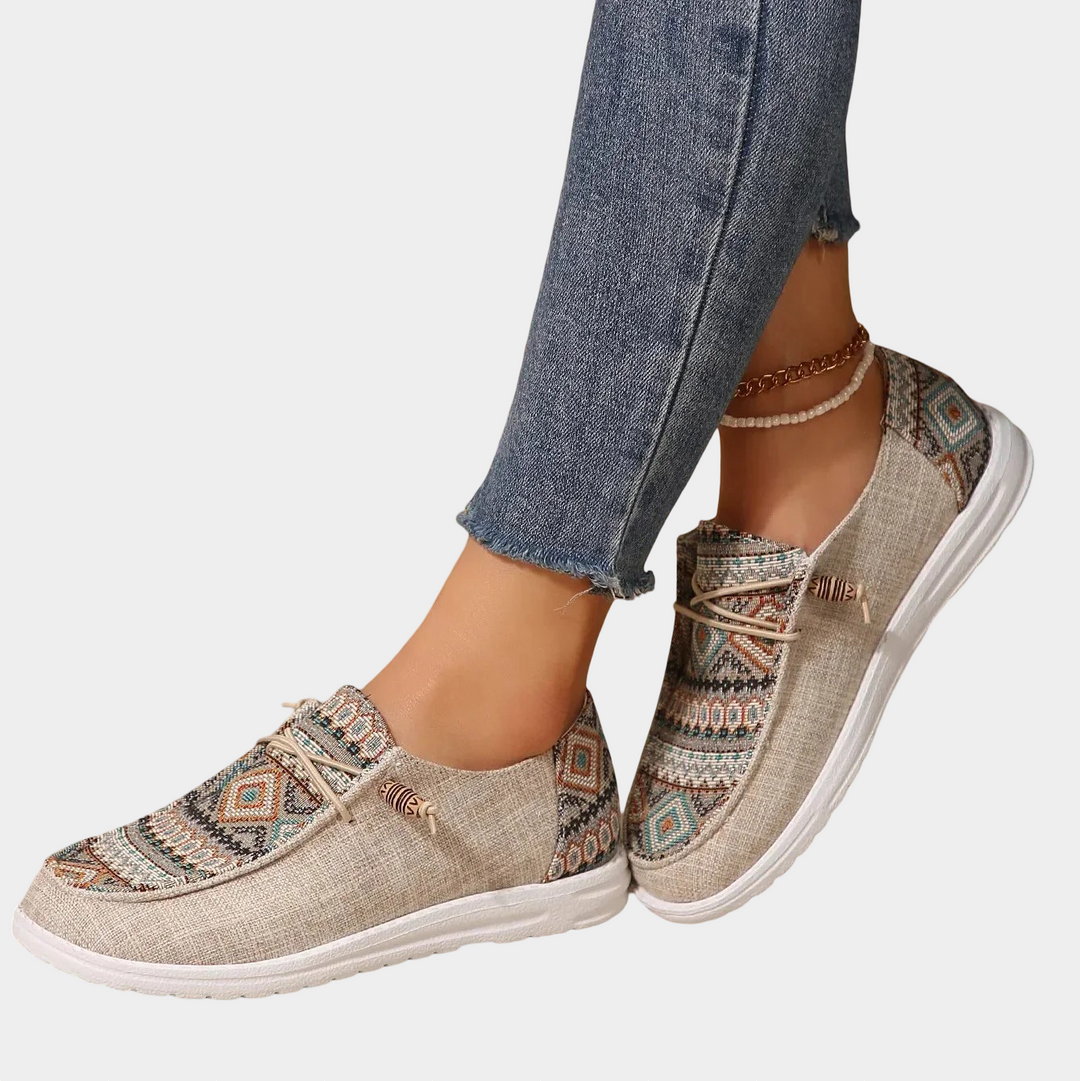 A woman wearing khaki boho-patterned lightweight trainers on a walk in town.