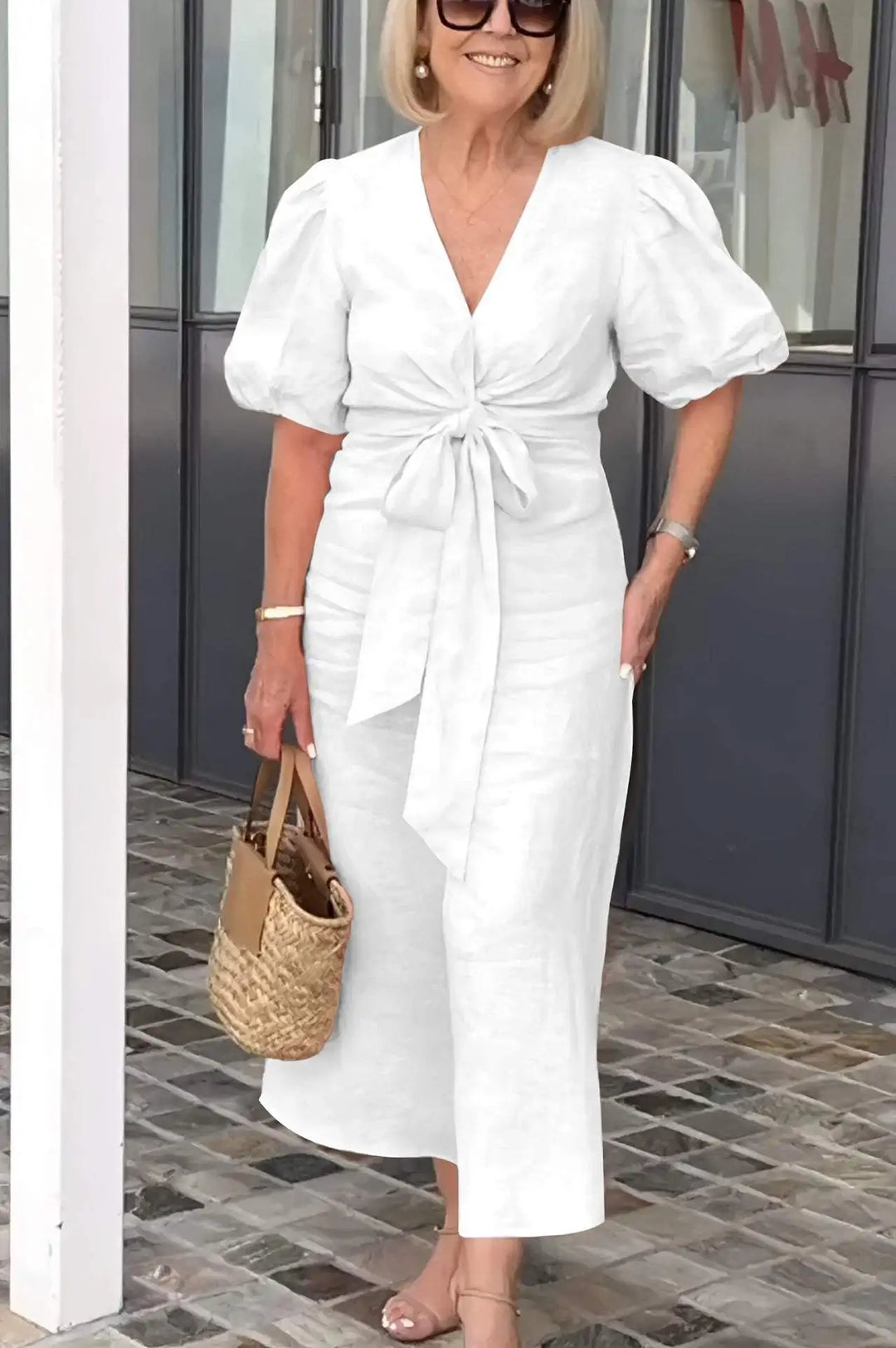 Woman wearing the Bridget bow-front midi dress with puff sleeves at a garden party.