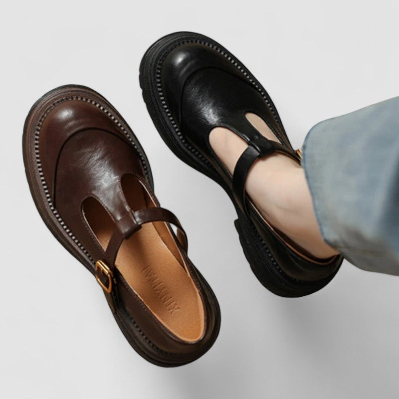 Woman wearing brown Mary Jane comfort shoes with a T-strap, standing on a city footpath.