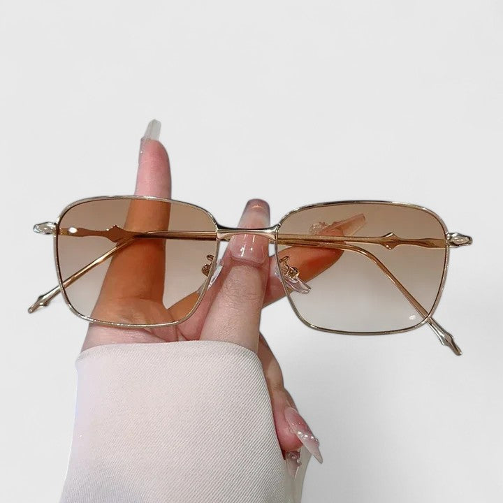 A woman on a sunny street wearing classic square gradient sunglasses, confident and stylish.