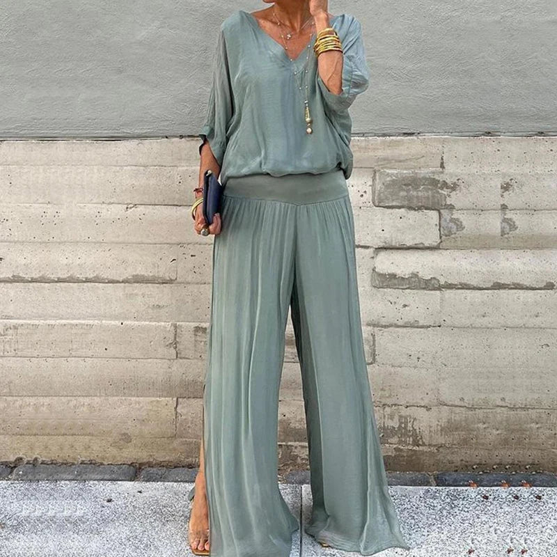 A woman wearing a flowing lounge two-piece set with a V-neck top and wide-leg trousers.