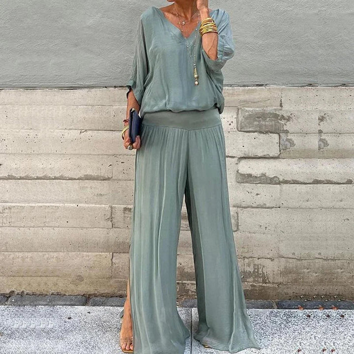 A woman wearing a flowing lounge two-piece set with a V-neck top and wide-leg trousers.