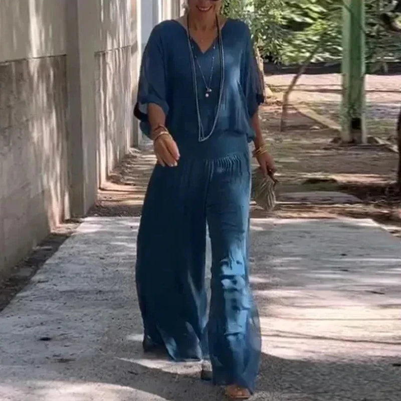 A woman wearing a flowing lounge two-piece set with a V-neck top and wide-leg trousers.
