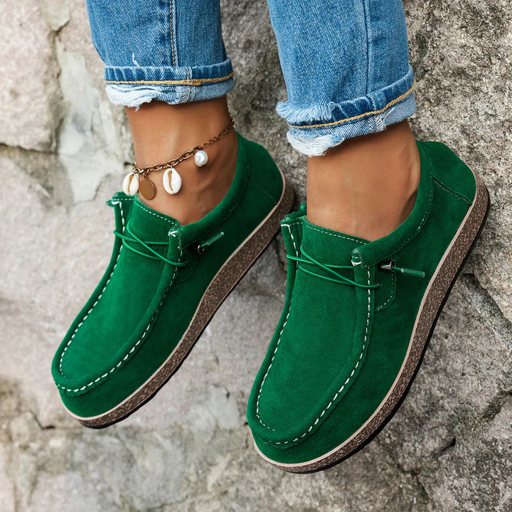 A woman wearing green boho-print lace-up comfort shoes on a walk through the garden.