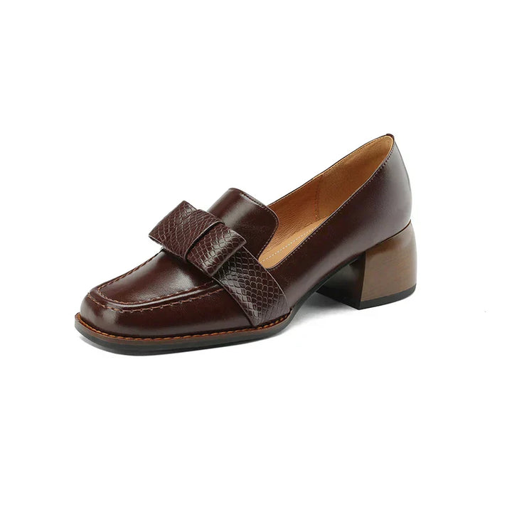 A woman wearing classic loafers with a subtle knot detail and tailored trousers