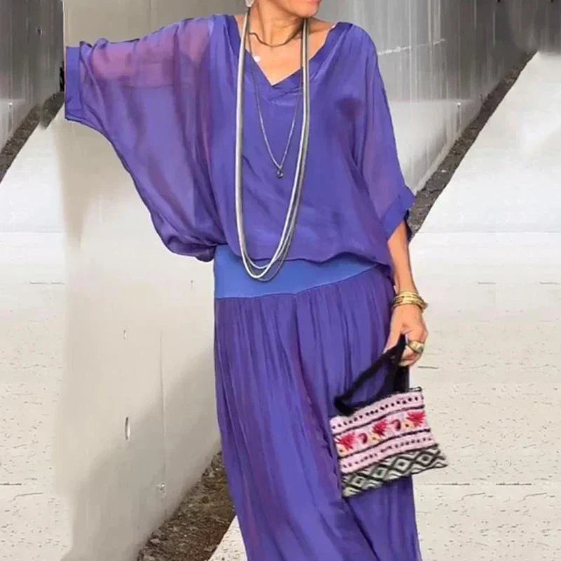 A woman wearing a flowing lounge two-piece set with a V-neck top and wide-leg trousers.