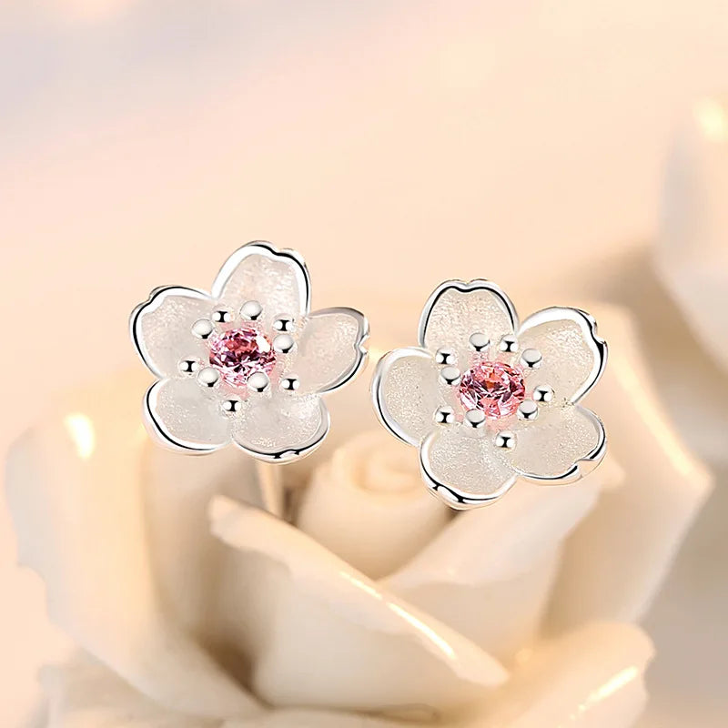 A pair of fine floral stud earrings in polished silver set with pink and purple zirconia stones