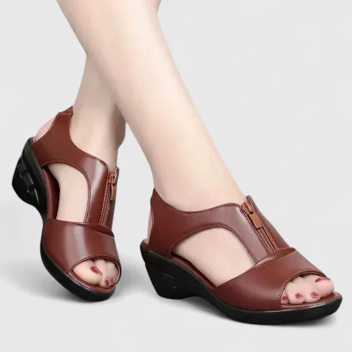 A woman wearing wine red elegant sandals with a broad, cushioned footbed.