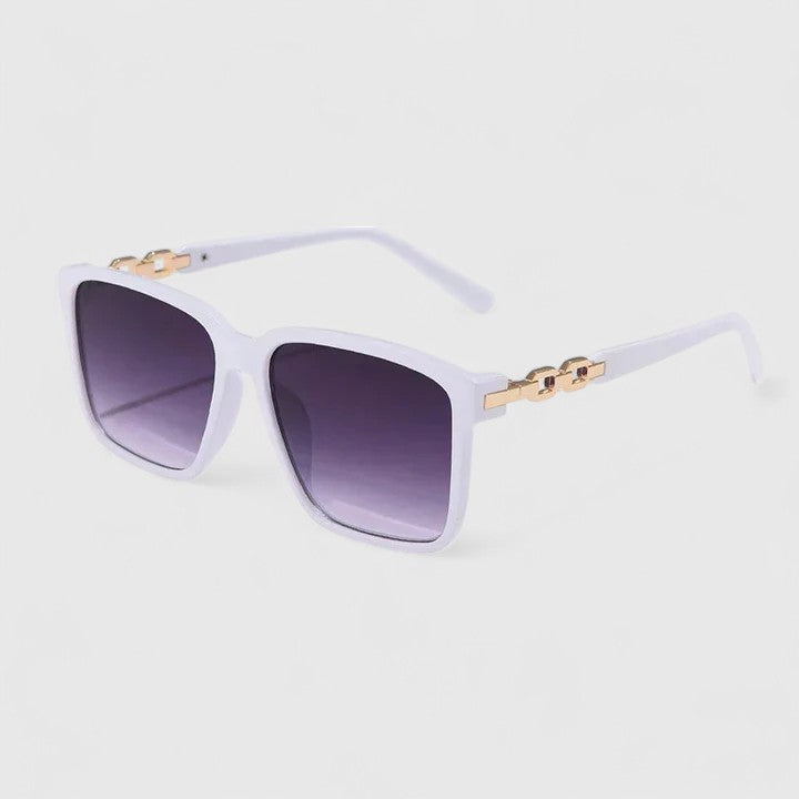 A woman by the pool wearing bold square sunglasses with chain-detail temples, confident in the sun.