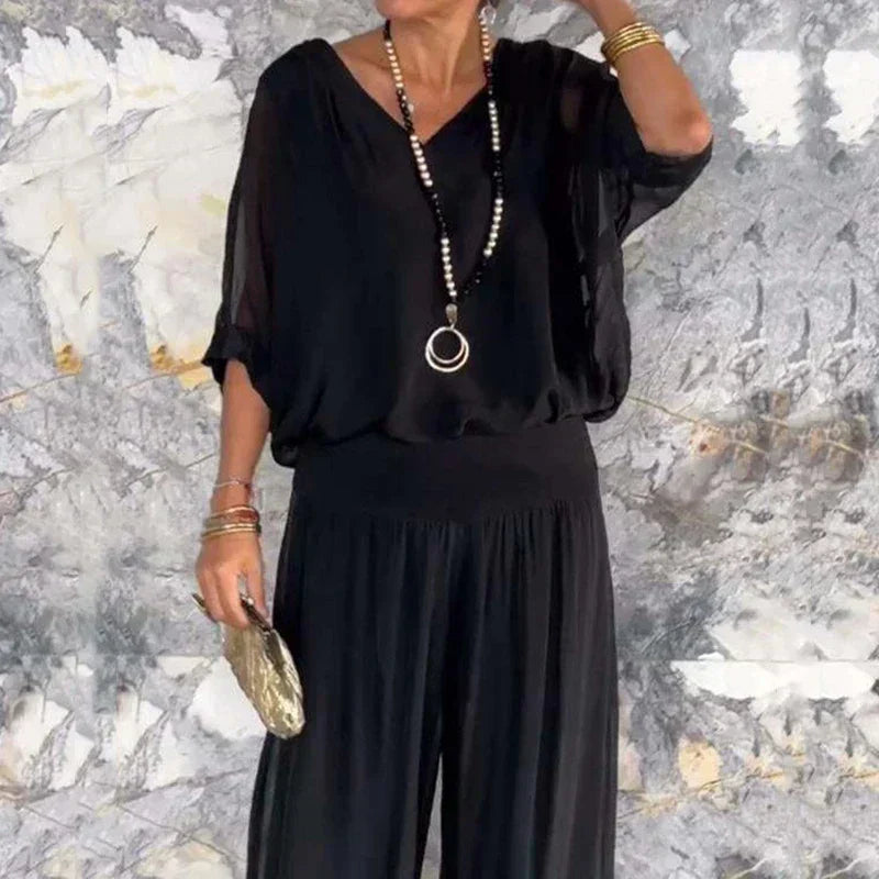 A woman wearing a flowing lounge two-piece set with a V-neck top and wide-leg trousers.
