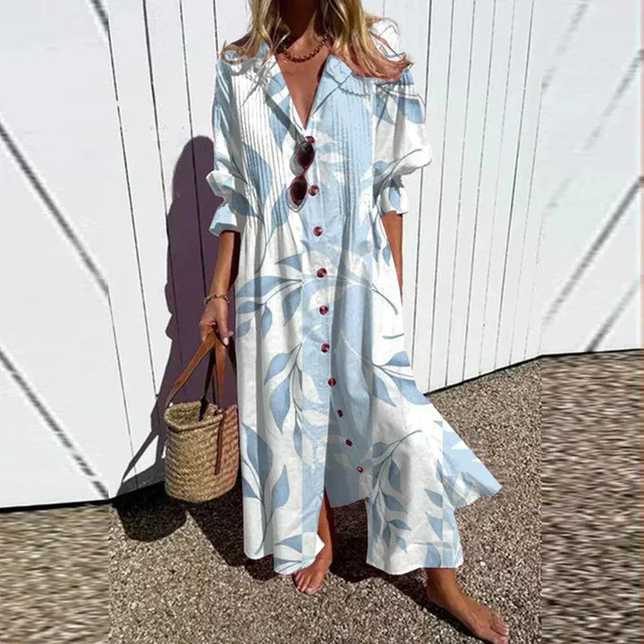 Woman wearing the Zara™ leaf print maxi dress with a button front, walking along the coast in a light breeze.