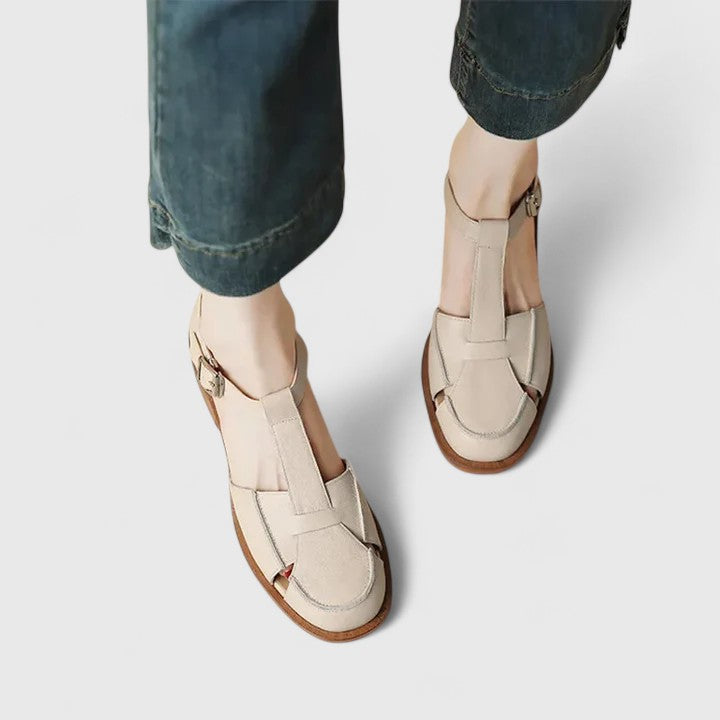 A woman wearing brown Mary Jane sandals with a T-strap and buckle, paired with a summer dress.