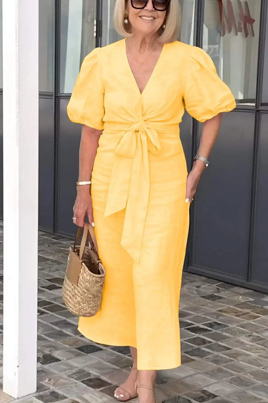 Woman wearing the Bridget bow-front midi dress with puff sleeves at a garden party.