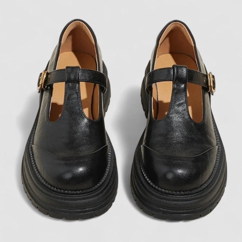 Woman wearing brown Mary Jane comfort shoes with a T-strap, standing on a city footpath.