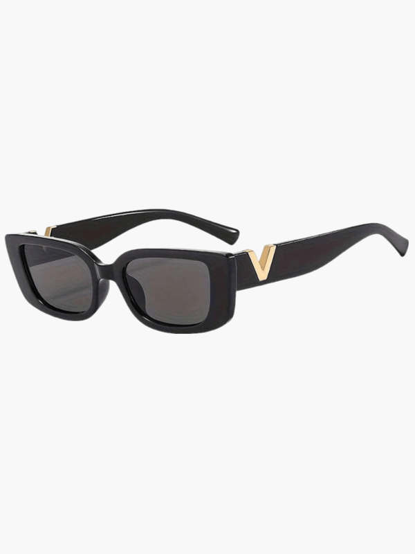 A woman at an outdoor event wearing chunky black rectangular retro sunglasses with a gold-tone accent.