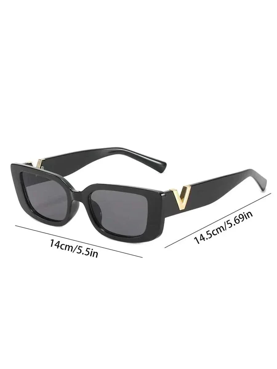 A woman at an outdoor event wearing chunky black rectangular retro sunglasses with a gold-tone accent.