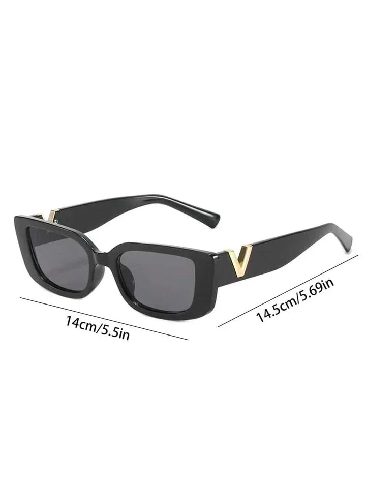 A woman at an outdoor event wearing chunky black rectangular retro sunglasses with a gold-tone accent.