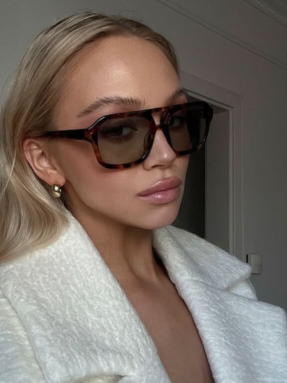 A woman wearing two-tone oval vintage sunglasses on a sunny day outdoors.