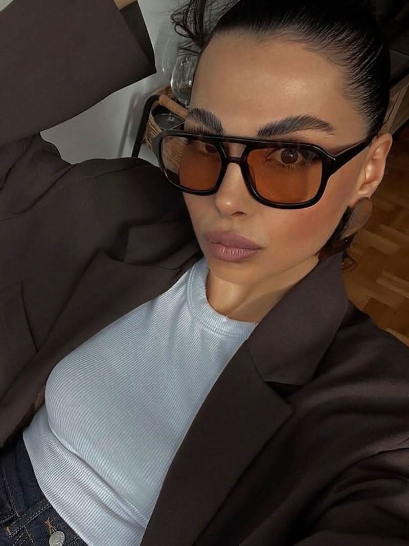 A woman wearing two-tone oval vintage sunglasses on a sunny day outdoors.