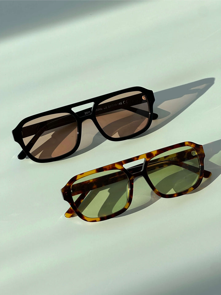 A woman wearing two-tone oval vintage sunglasses on a sunny day outdoors.