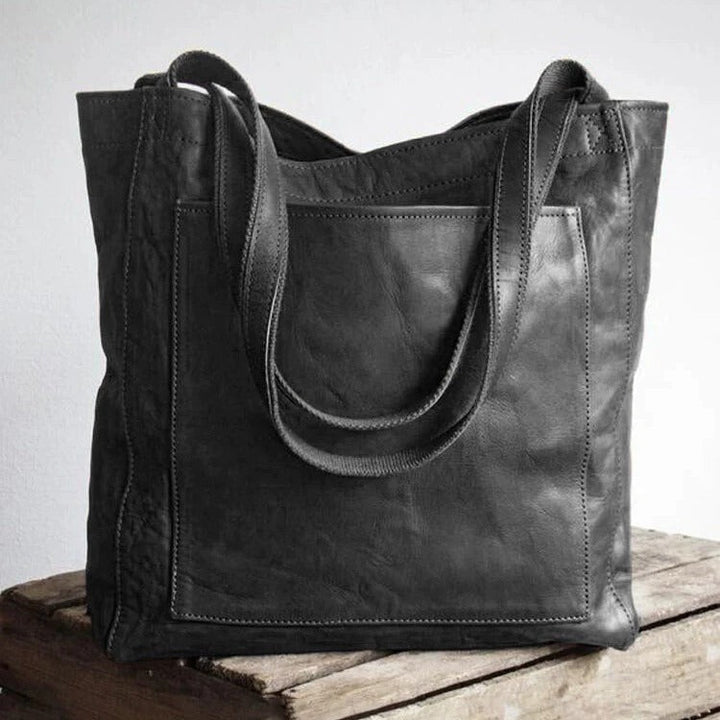 A woman holding a classic handbag with a rich finish by her side
