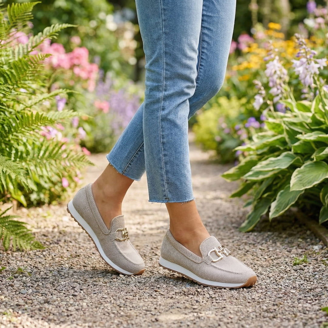 A woman in smart-casual orthopaedic loafer trainers with a subtle golden detail.