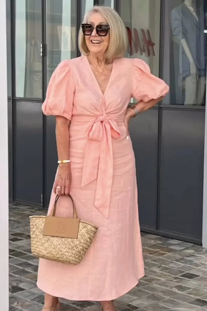 Woman wearing the Bridget bow-front midi dress with puff sleeves at a garden party.