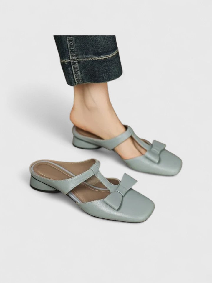 A woman wearing soft pink comfort sandals with a broad, cushioned footbed on a sunny day.
