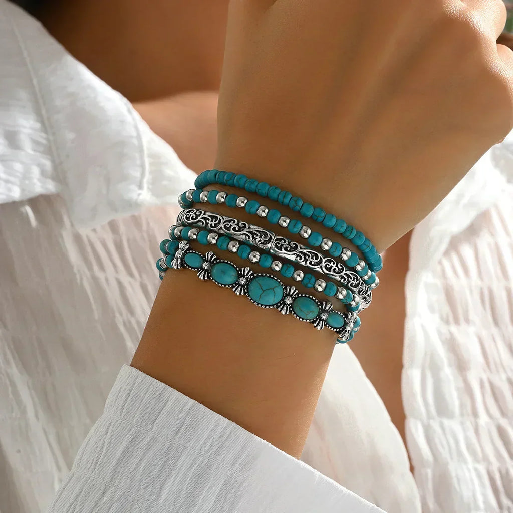 Set of turquoise and metallic boho-style stacking bracelets on a white background
