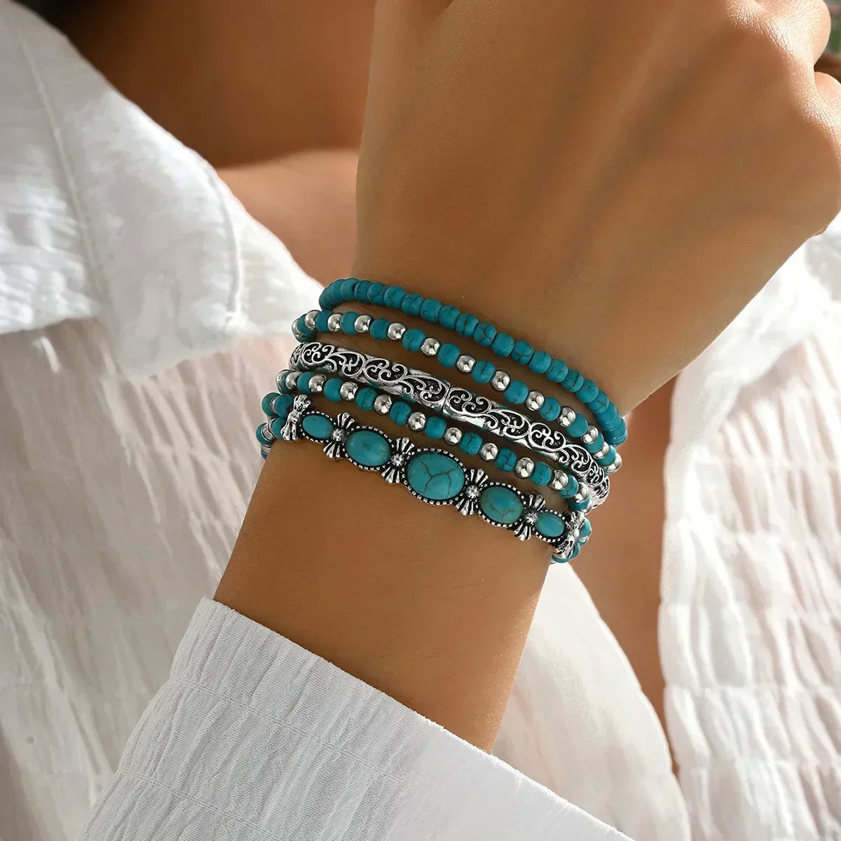 Set of turquoise and metallic boho-style stacking bracelets on a white background