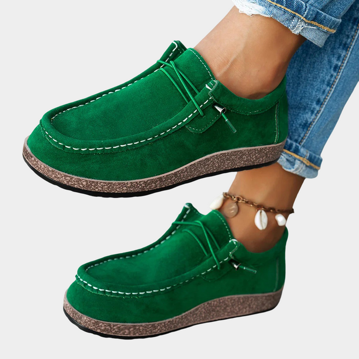A woman wearing green boho-print lace-up comfort shoes on a walk through the garden.
