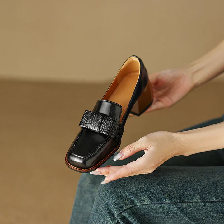 A woman wearing classic loafers with a subtle knot detail and tailored trousers