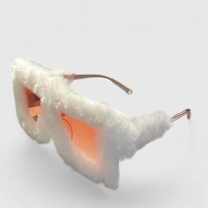 A woman on a bright winter walk wearing lightweight stylish sunglasses, smiling easily.