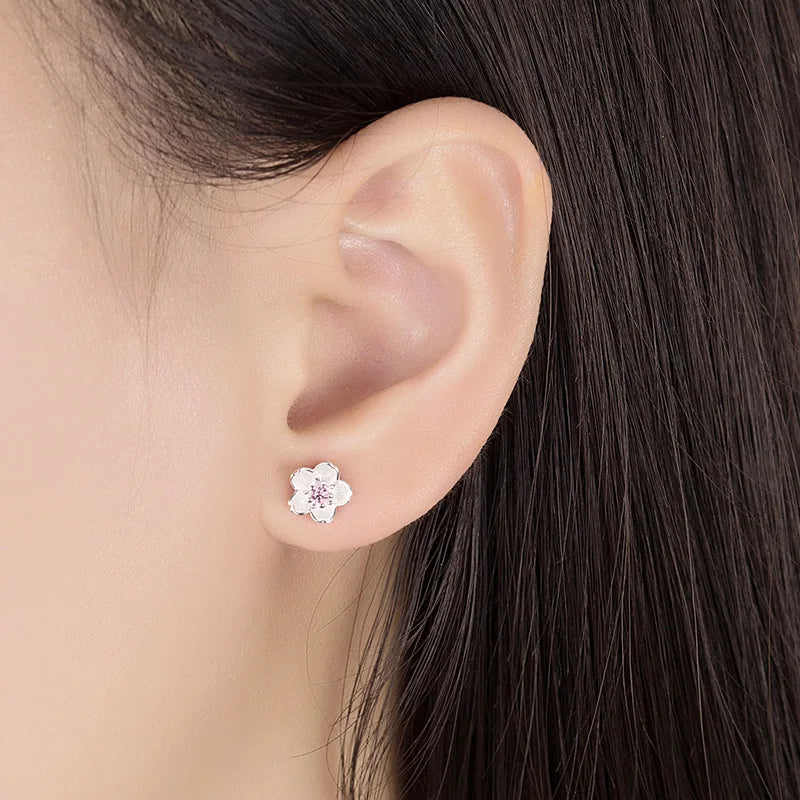 A pair of fine floral stud earrings in polished silver set with pink and purple zirconia stones