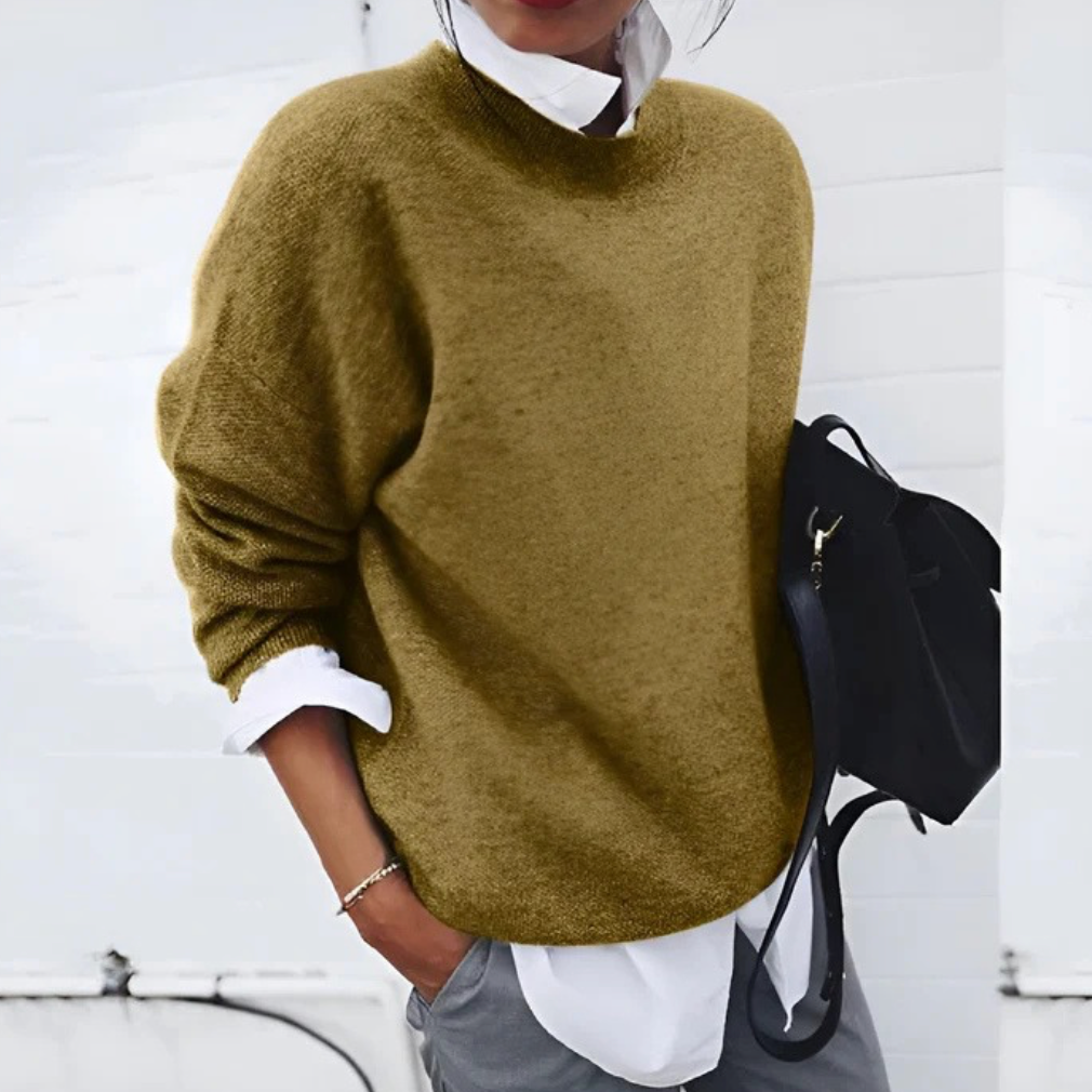 A woman wearing a soft mustard round-neck jumper with an elegant modern shape, relaxed and warm.