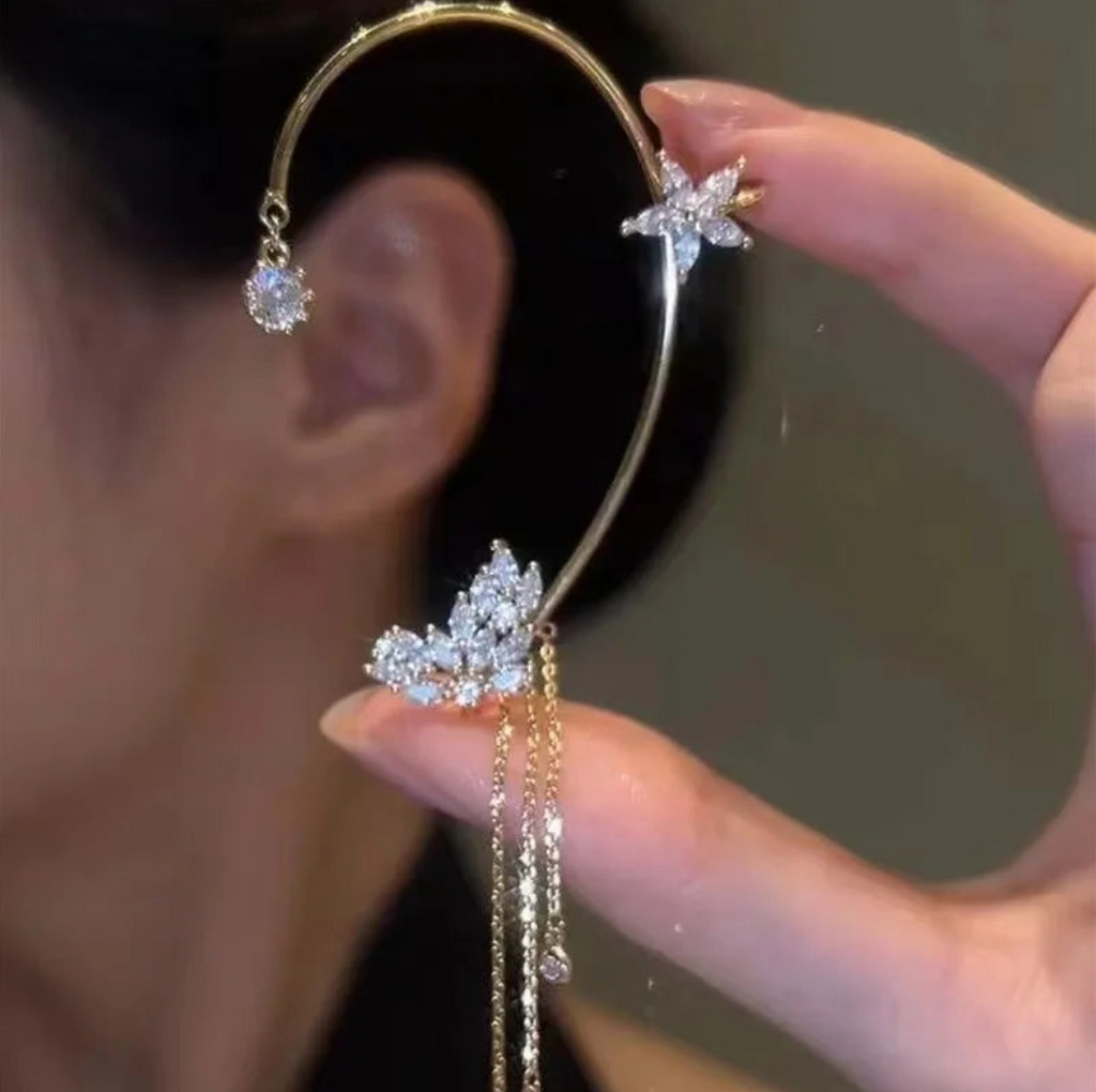 Gold celestial arc earring with a butterfly detail, framing the ear with sparkling luminosity