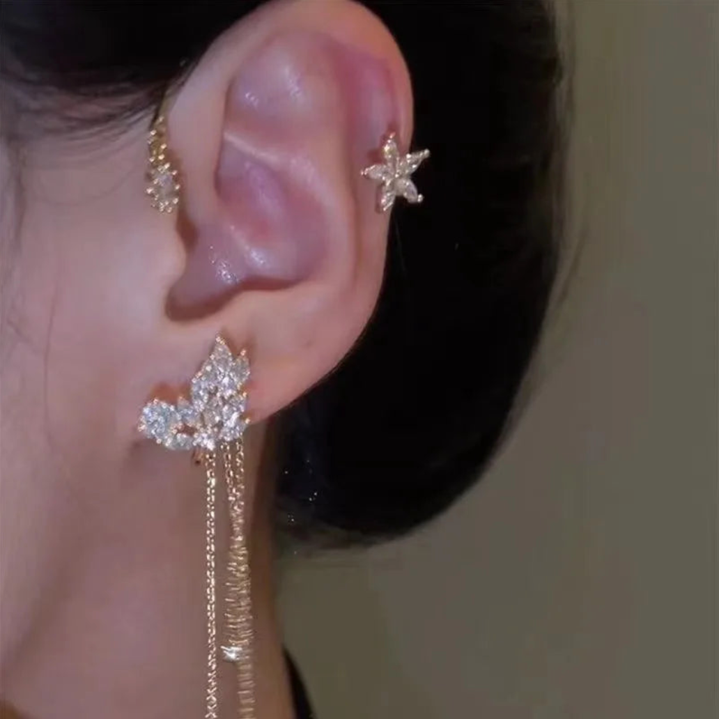 Gold celestial arc earring with a butterfly detail, framing the ear with sparkling luminosity