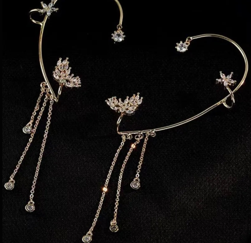 Gold celestial arc earring with a butterfly detail, framing the ear with sparkling luminosity