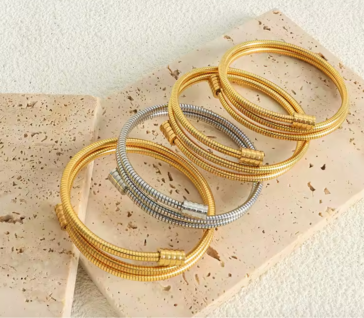 Twisted gold bracelet in gold and silver tones on a plain background