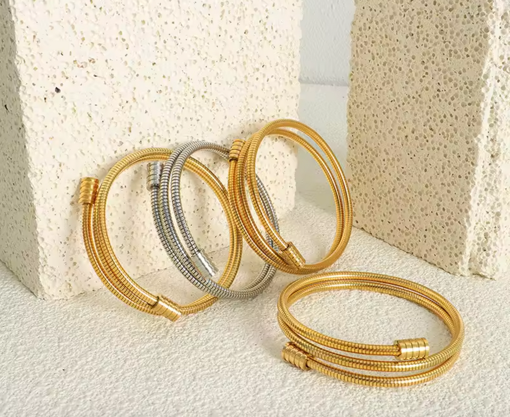 Twisted gold bracelet in gold and silver tones on a plain background