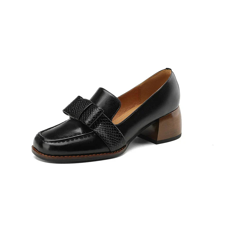 A woman wearing classic loafers with a subtle knot detail and tailored trousers